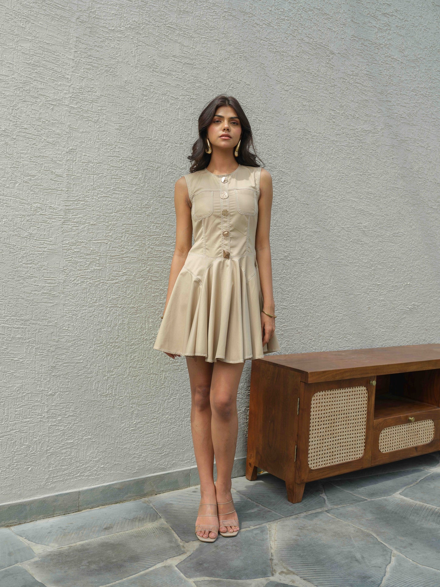 BLUSH – A short buff-colored dress featuring metal button detailing for a sleek, modern look