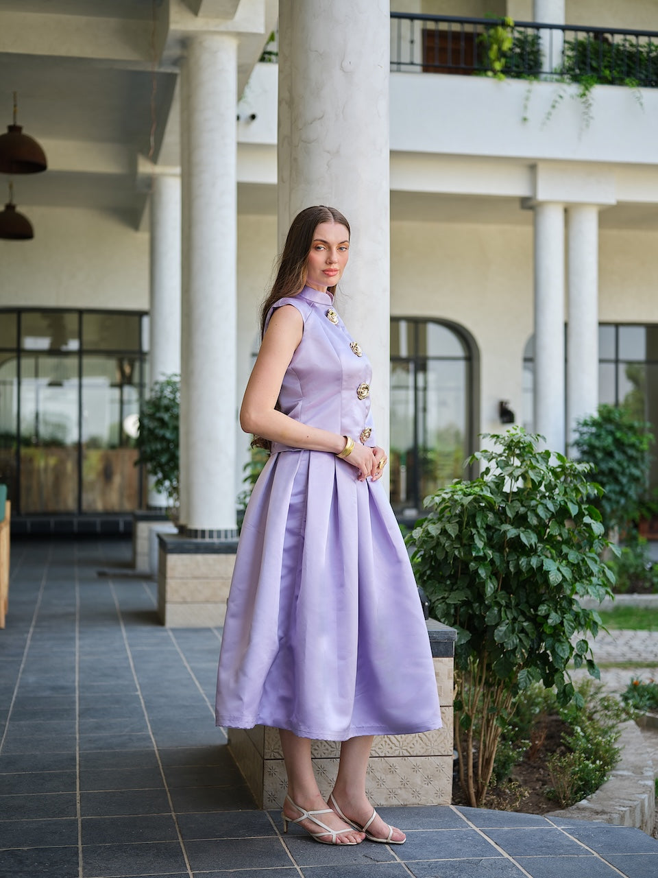 VIRELLE- A lavender sleeveless jacket with metal floral buttons paired with a box pleat skirt.
