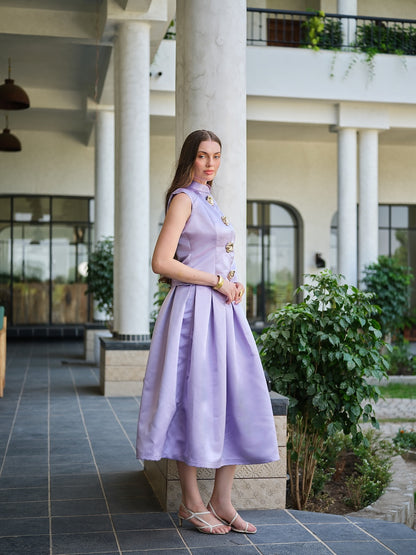 VIRELLE- A lavender sleeveless jacket with metal floral buttons paired with a box pleat skirt.