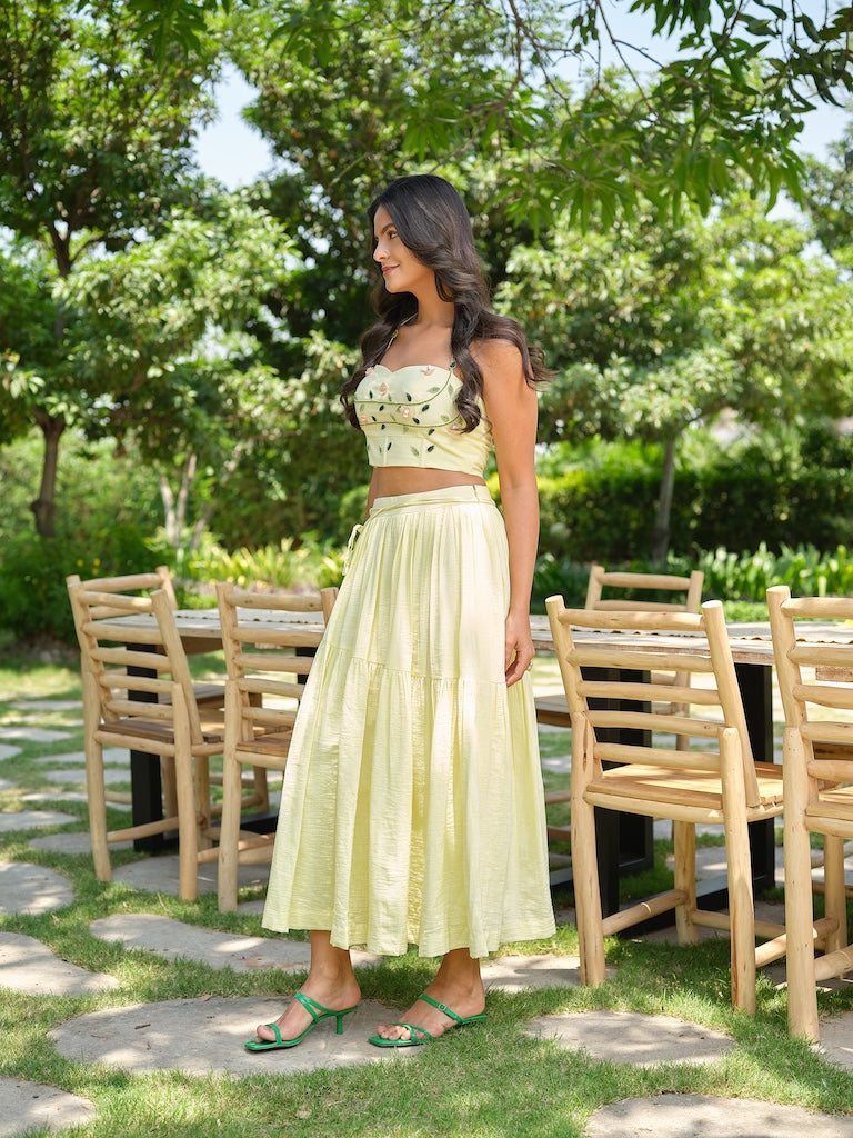 VENTORE- A yellow top adorned with intricate embroidery, enhanced with corset-style detailing for a structured fit. Paired with a layered gathered skirt