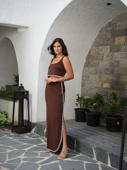 WESTORA - A brown top featuring delicate stone detailing along the hem for a subtle shimmer. Paired with a straight skirt adorned with matching side stone accents and sleek side slits.