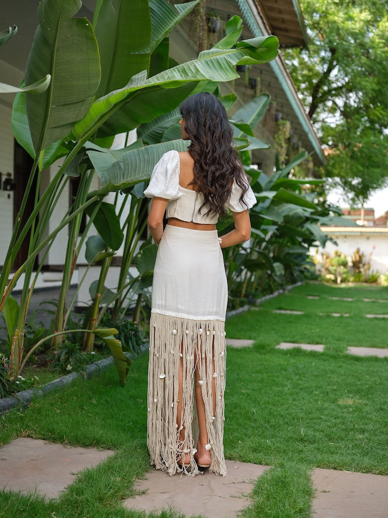 LAVIQUE - An ivory pleated co-ord with floral detailing and a tasseled skirt.