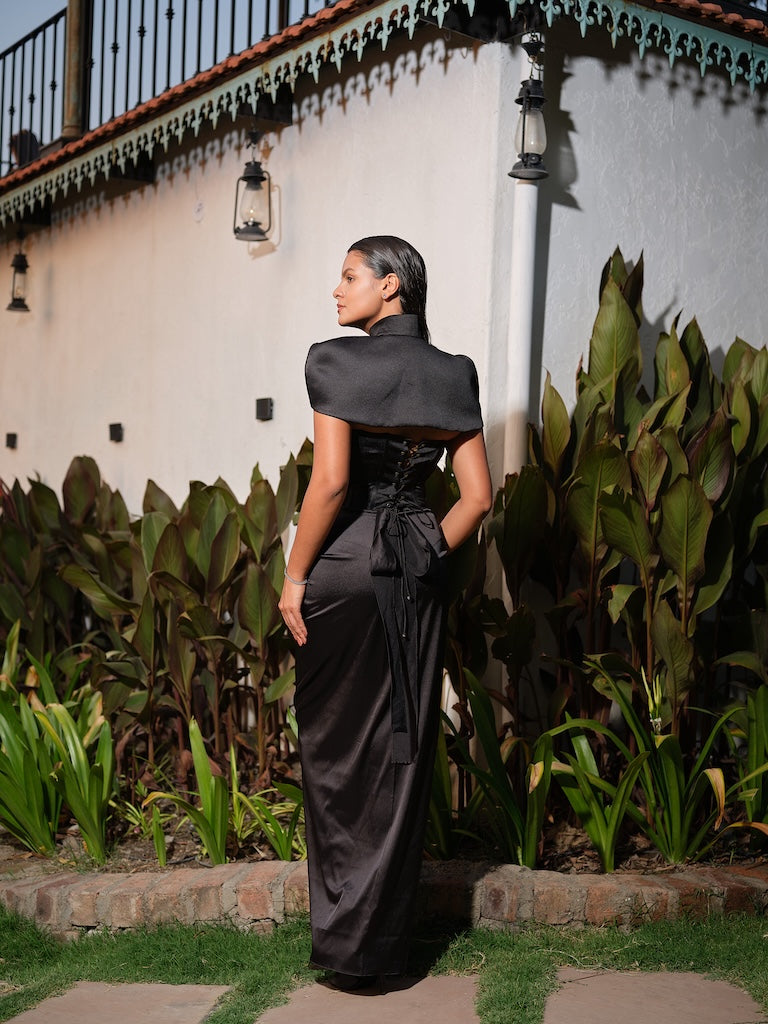 ELIORA - A black corset with intricate stone embellishments, layered with a statement cape jacket featuring scattered stone work. Paired with a self-tie drape skirt
