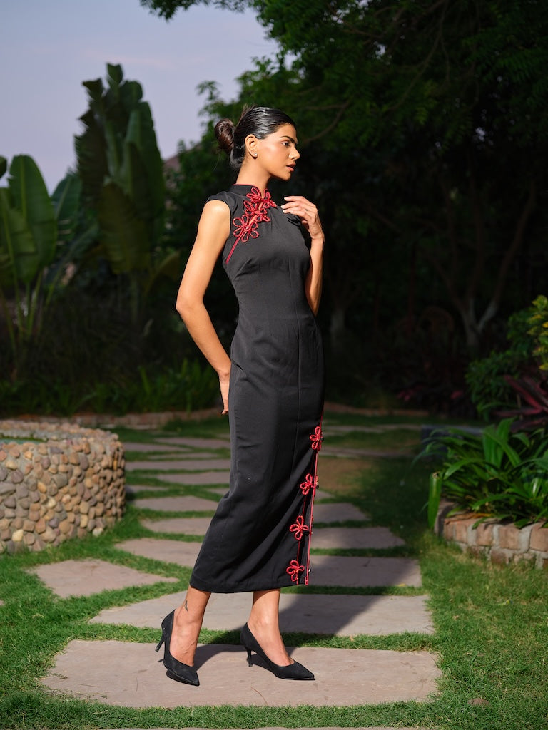 VESPERA - A black dress with a mandarin collar, highlighted by striking red piping details. Featuring a subtle neckline cut, a front slit, and a black stone-embellished bow for a refined edge.