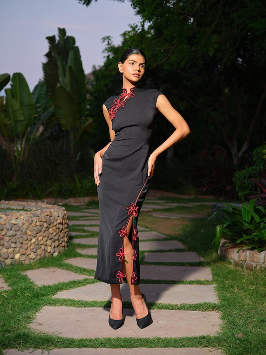 VESPERA - A black dress with a mandarin collar, highlighted by striking red piping details. Featuring a subtle neckline cut, a front slit, and a black stone-embellished bow for a refined edge.